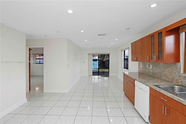 kitchen with decorative backsplash, white dishwasher, light tile patterned flooring, and sink