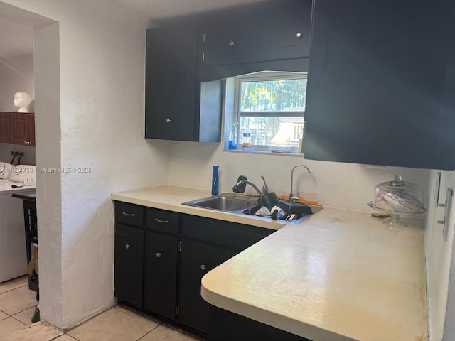 kitchen featuring washer and clothes dryer, sink, and light tile patterned floors