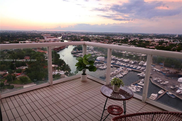 balcony at dusk featuring a water view