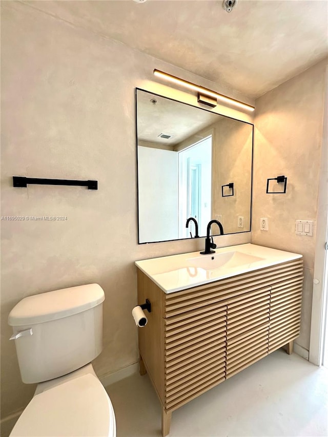 bathroom featuring vanity, toilet, and concrete flooring