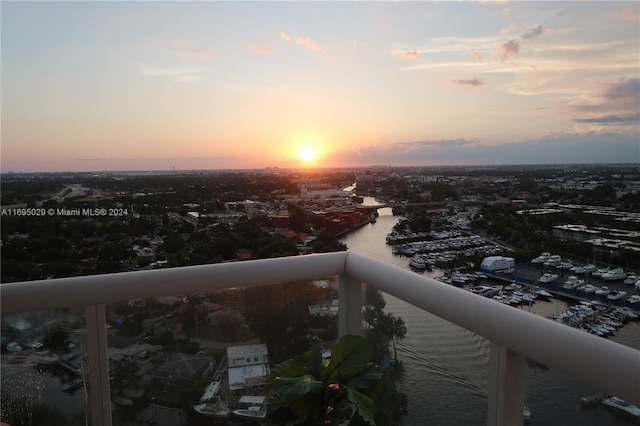 balcony at dusk featuring a water view