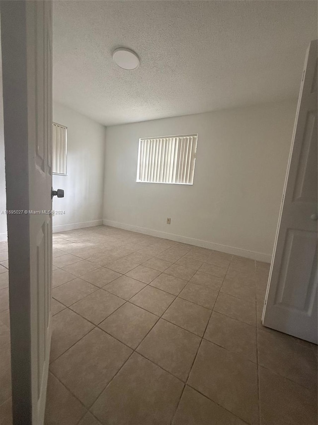 spare room featuring light tile patterned floors and a textured ceiling