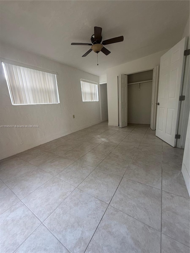 unfurnished bedroom featuring ceiling fan, a closet, and light tile patterned floors