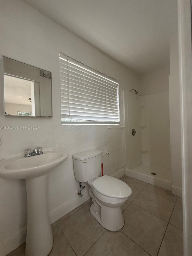 bathroom featuring tile patterned flooring, toilet, walk in shower, and sink