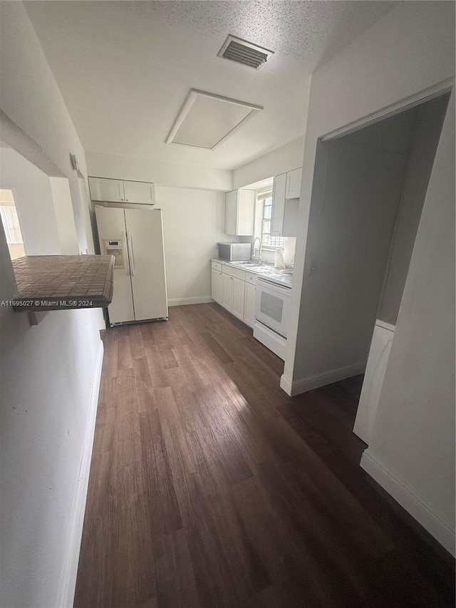 kitchen with white appliances, white cabinets, sink, dark hardwood / wood-style floors, and a textured ceiling