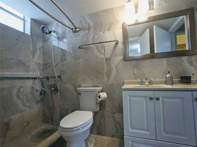 bathroom with vanity, toilet, a tile shower, and tile walls