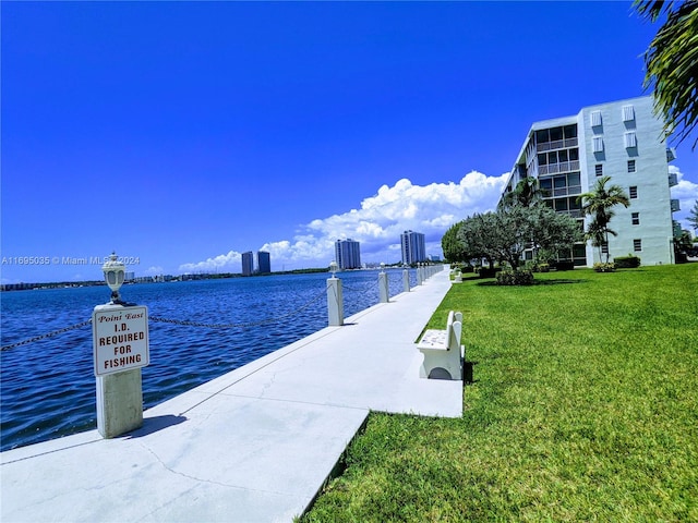 view of dock with a water view and a lawn