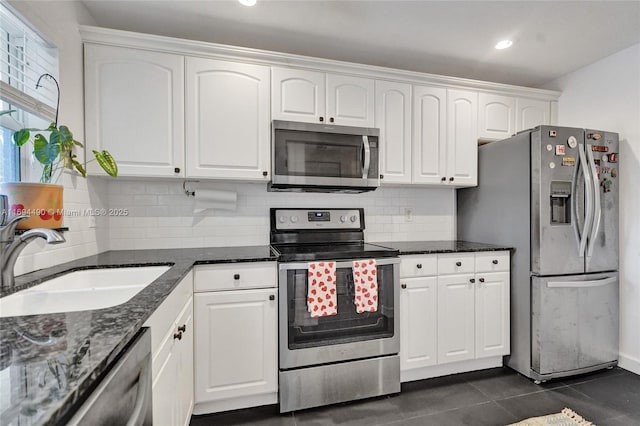 kitchen featuring dark tile patterned floors, sink, white cabinetry, and stainless steel appliances