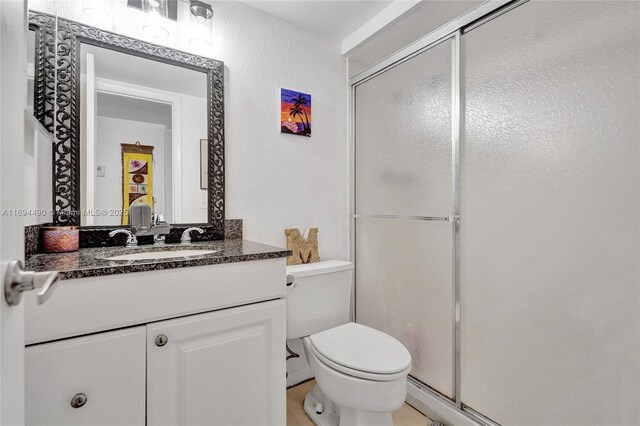 bathroom featuring vanity, a shower with shower door, and toilet