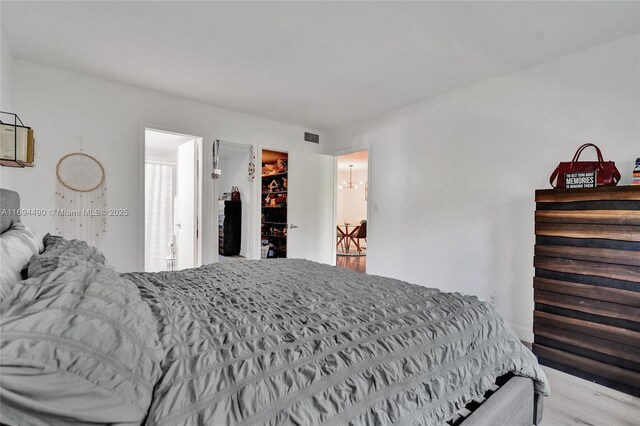 bedroom featuring a walk in closet, light hardwood / wood-style floors, and a closet