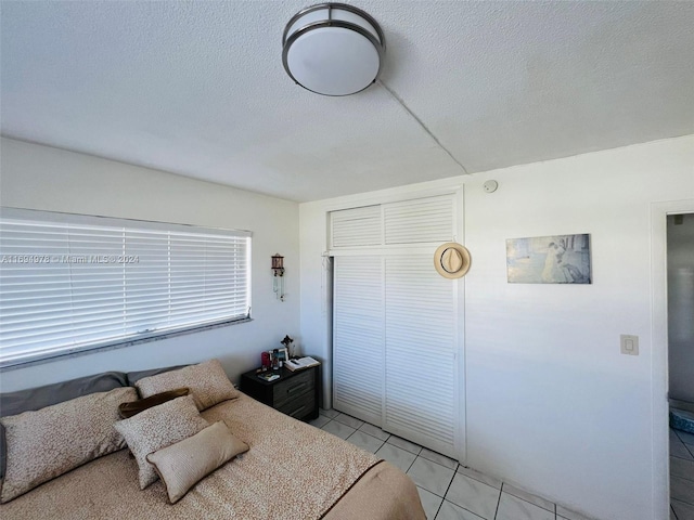 tiled bedroom with a textured ceiling and a closet