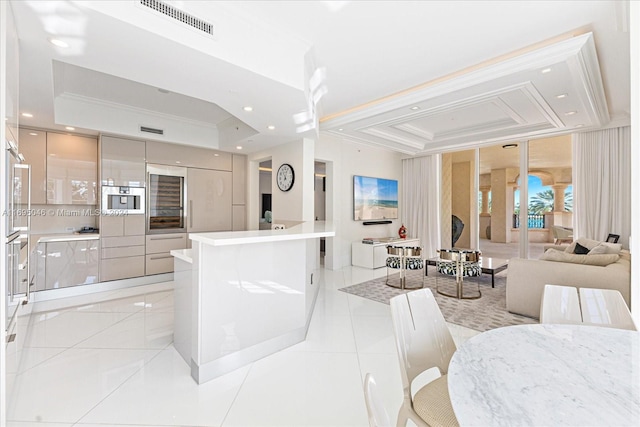 kitchen featuring a center island, white cabinets, a raised ceiling, crown molding, and light tile patterned floors