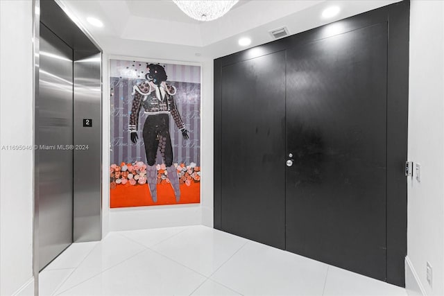 corridor with light tile patterned floors and a tray ceiling