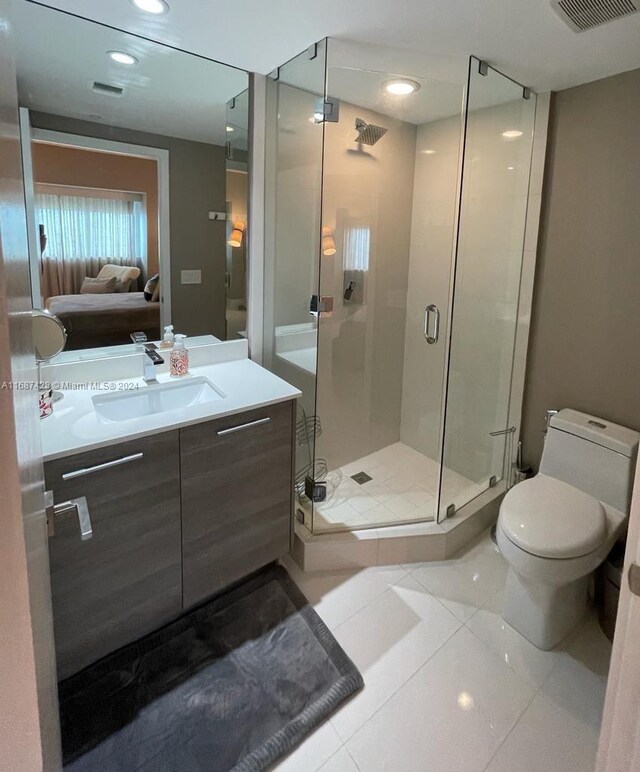 bathroom with tile patterned flooring, vanity, toilet, and a shower with door