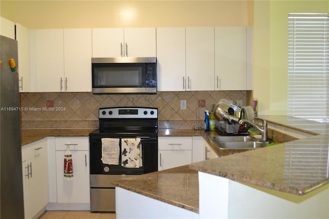 kitchen featuring dark stone counters, sink, decorative backsplash, appliances with stainless steel finishes, and white cabinetry