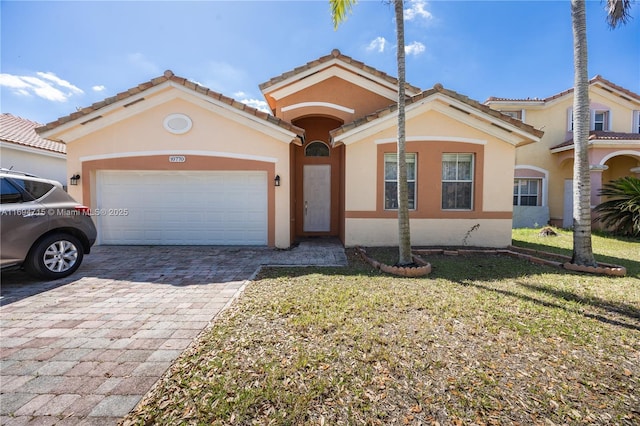 mediterranean / spanish-style home featuring a tiled roof, decorative driveway, a garage, a front lawn, and stucco siding