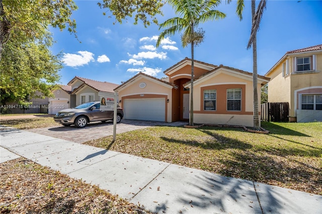 mediterranean / spanish home featuring driveway, a front yard, stucco siding, fence, and a garage