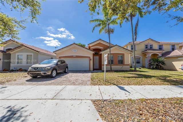 mediterranean / spanish-style house featuring stucco siding, a front yard, driveway, and a garage
