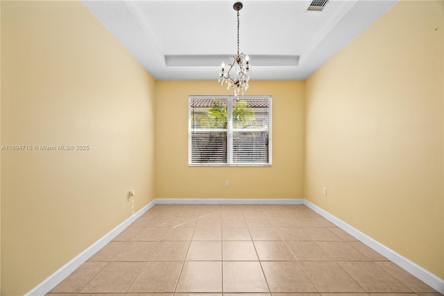 empty room with baseboards, visible vents, a notable chandelier, and a raised ceiling