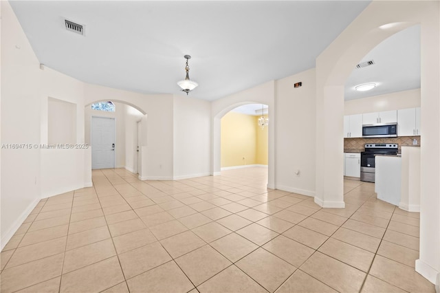 spare room featuring baseboards, visible vents, arched walkways, and light tile patterned floors