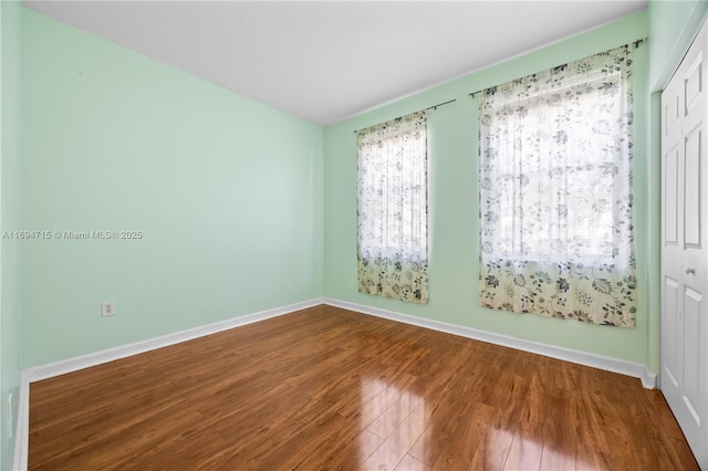 unfurnished room with baseboards and wood finished floors