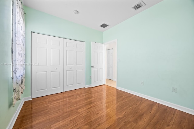 unfurnished bedroom featuring baseboards, visible vents, and wood finished floors