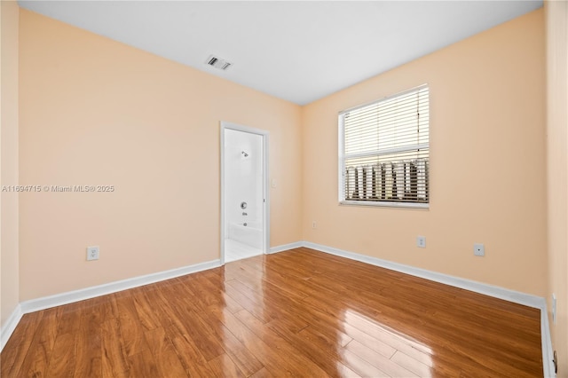 empty room with baseboards, visible vents, and wood finished floors