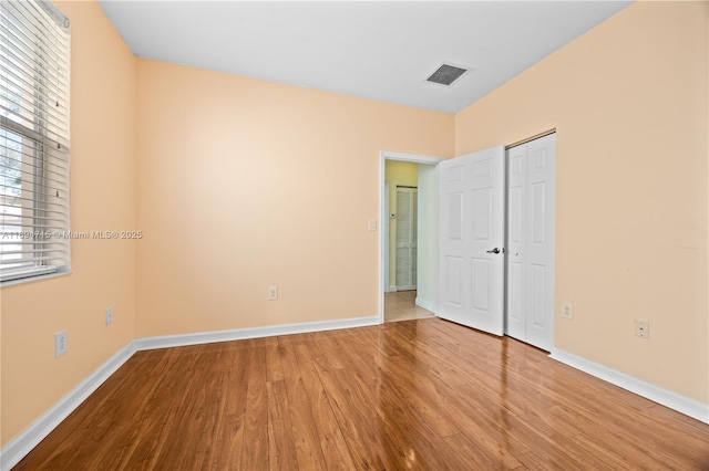 unfurnished bedroom with baseboards, wood finished floors, and multiple windows
