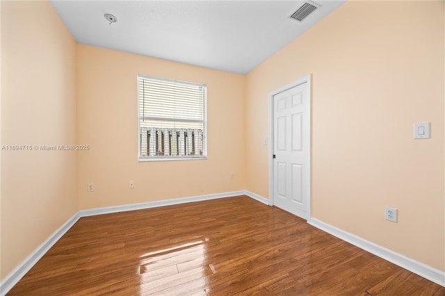 empty room featuring visible vents, baseboards, and wood finished floors