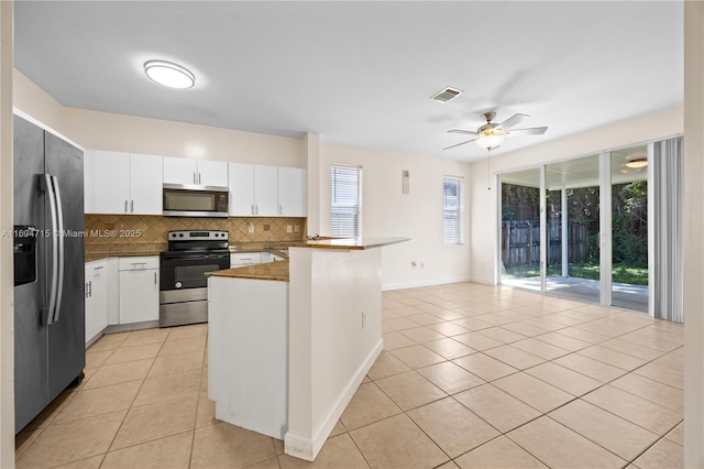 kitchen featuring light tile patterned flooring, tasteful backsplash, appliances with stainless steel finishes, a peninsula, and visible vents