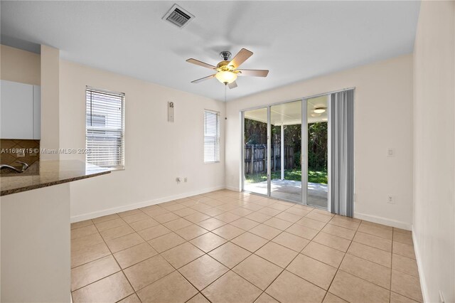 spare room featuring baseboards, ceiling fan, visible vents, and light tile patterned floors
