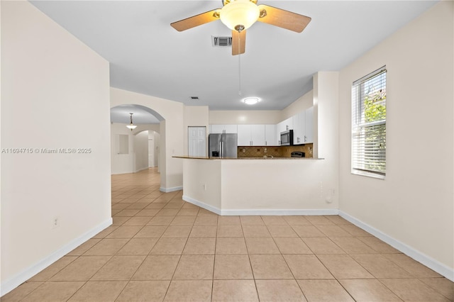 kitchen with stainless steel appliances, visible vents, white cabinets, arched walkways, and decorative backsplash