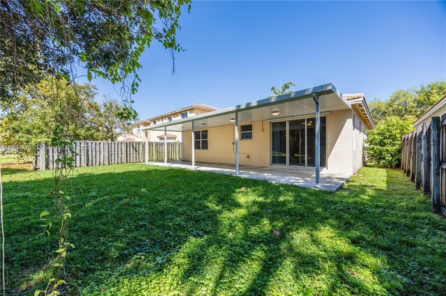 rear view of house featuring a fenced backyard, a lawn, stucco siding, and a patio