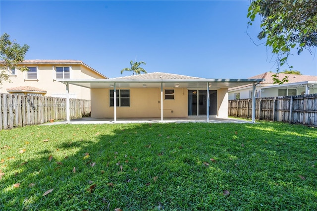 back of house featuring a lawn, stucco siding, and a patio