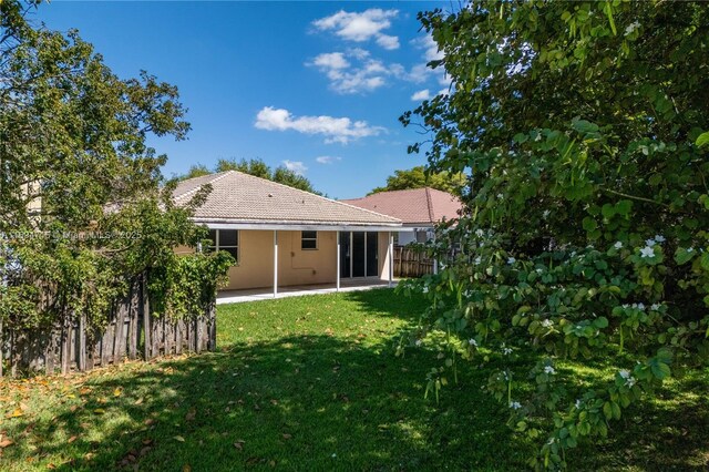 back of property featuring fence, a tiled roof, a patio, stucco siding, and a yard