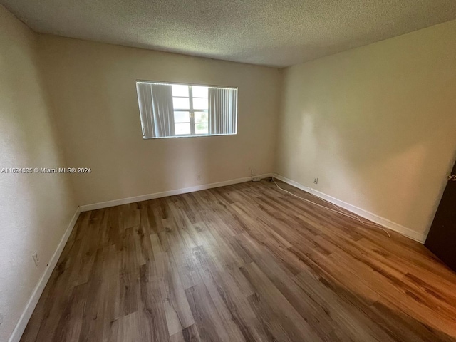 empty room with a textured ceiling and light wood-type flooring