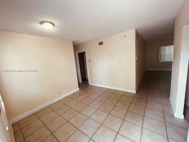 empty room featuring light tile patterned flooring and a textured ceiling