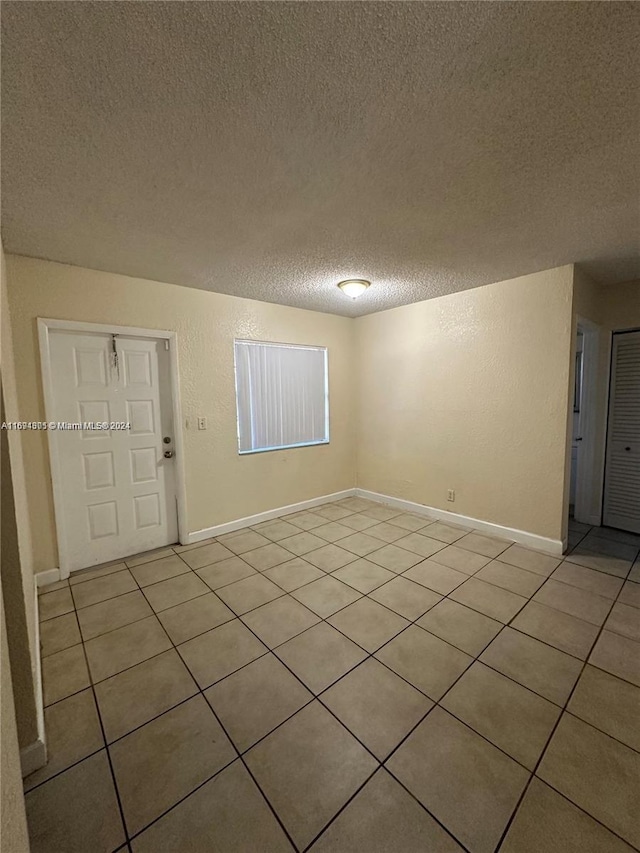 tiled empty room featuring a textured ceiling