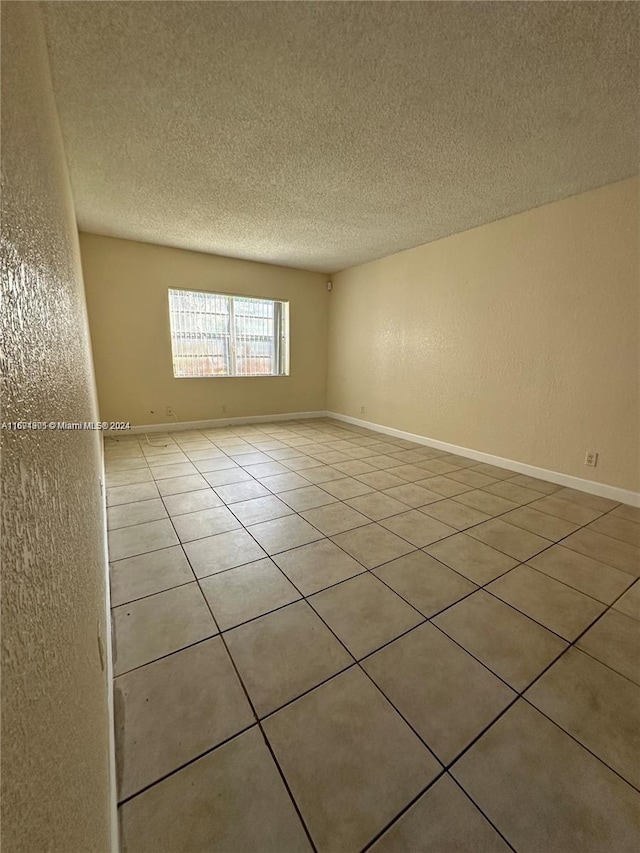 tiled spare room featuring a textured ceiling