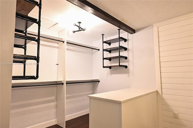 spacious closet featuring beamed ceiling and dark wood-type flooring