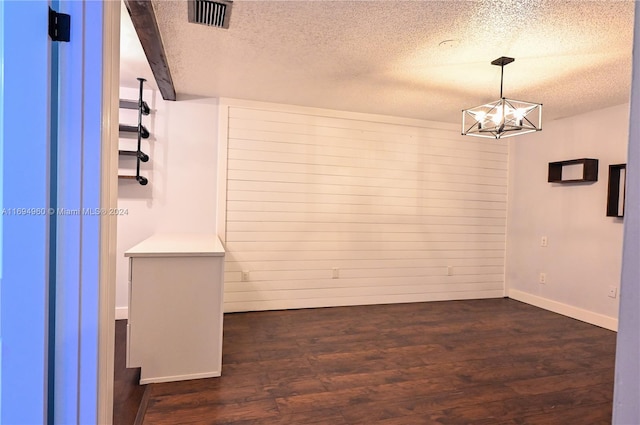 unfurnished room featuring dark hardwood / wood-style flooring, a textured ceiling, and an inviting chandelier