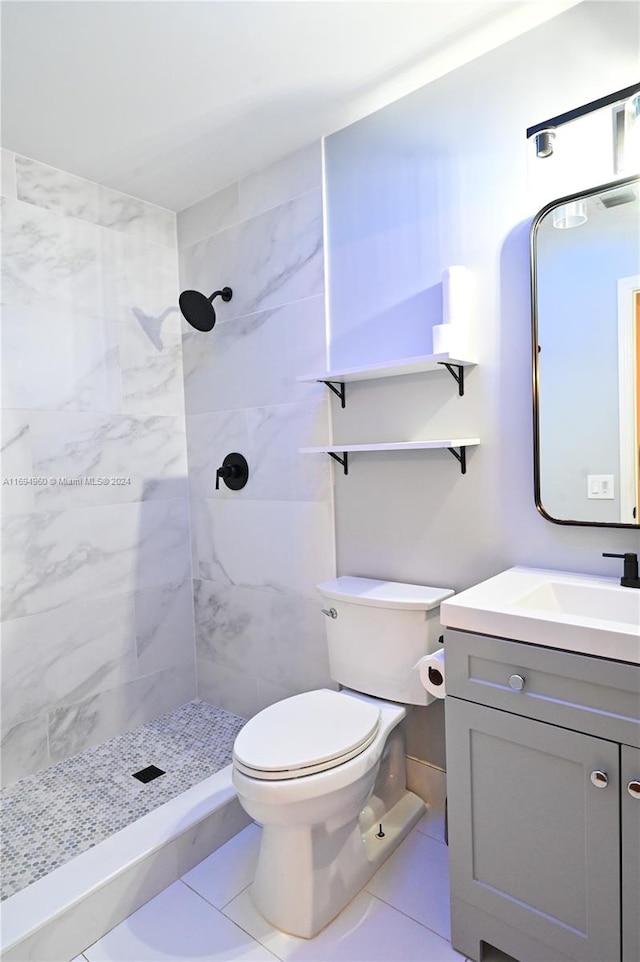 bathroom featuring a tile shower, tile patterned flooring, vanity, and toilet