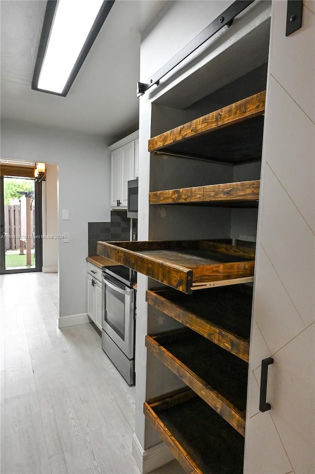 kitchen with stainless steel electric range, light hardwood / wood-style floors, and white cabinetry