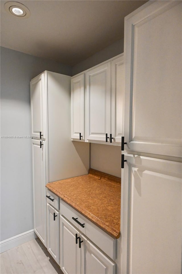 interior space with white cabinets and light hardwood / wood-style flooring