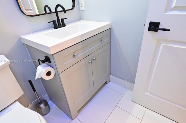 bathroom with toilet, vanity, and tile patterned floors