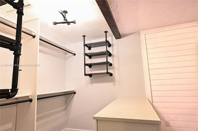 walk in closet featuring beam ceiling