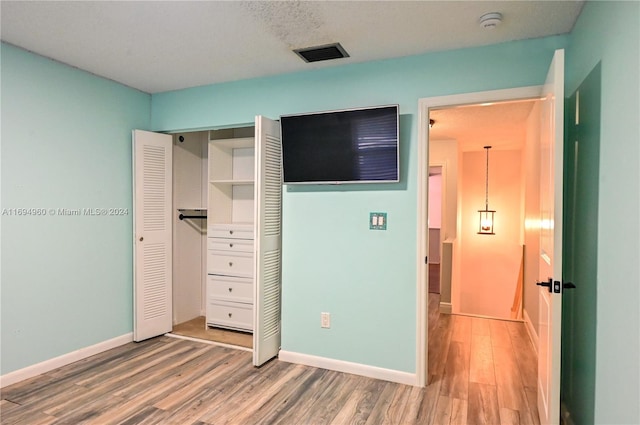 unfurnished bedroom with hardwood / wood-style floors, a textured ceiling, and a closet