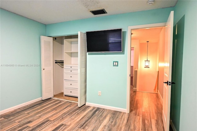 unfurnished bedroom featuring hardwood / wood-style floors and a closet