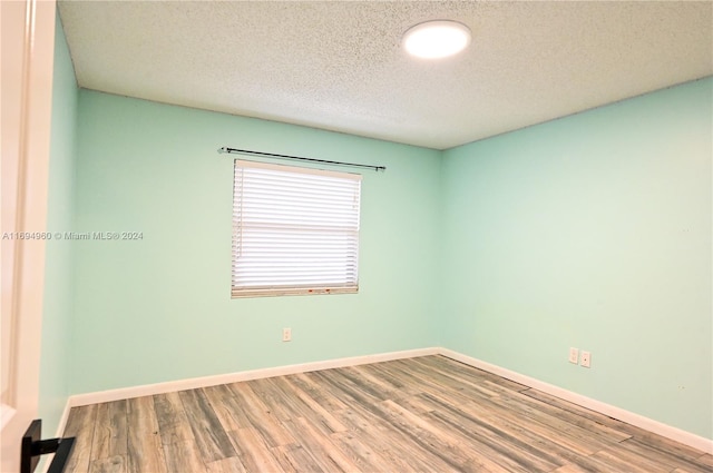 unfurnished room featuring a textured ceiling and hardwood / wood-style flooring