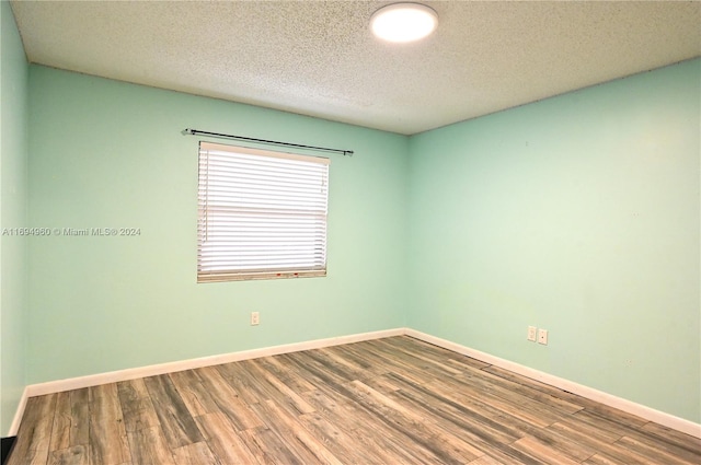 spare room featuring hardwood / wood-style floors and a textured ceiling